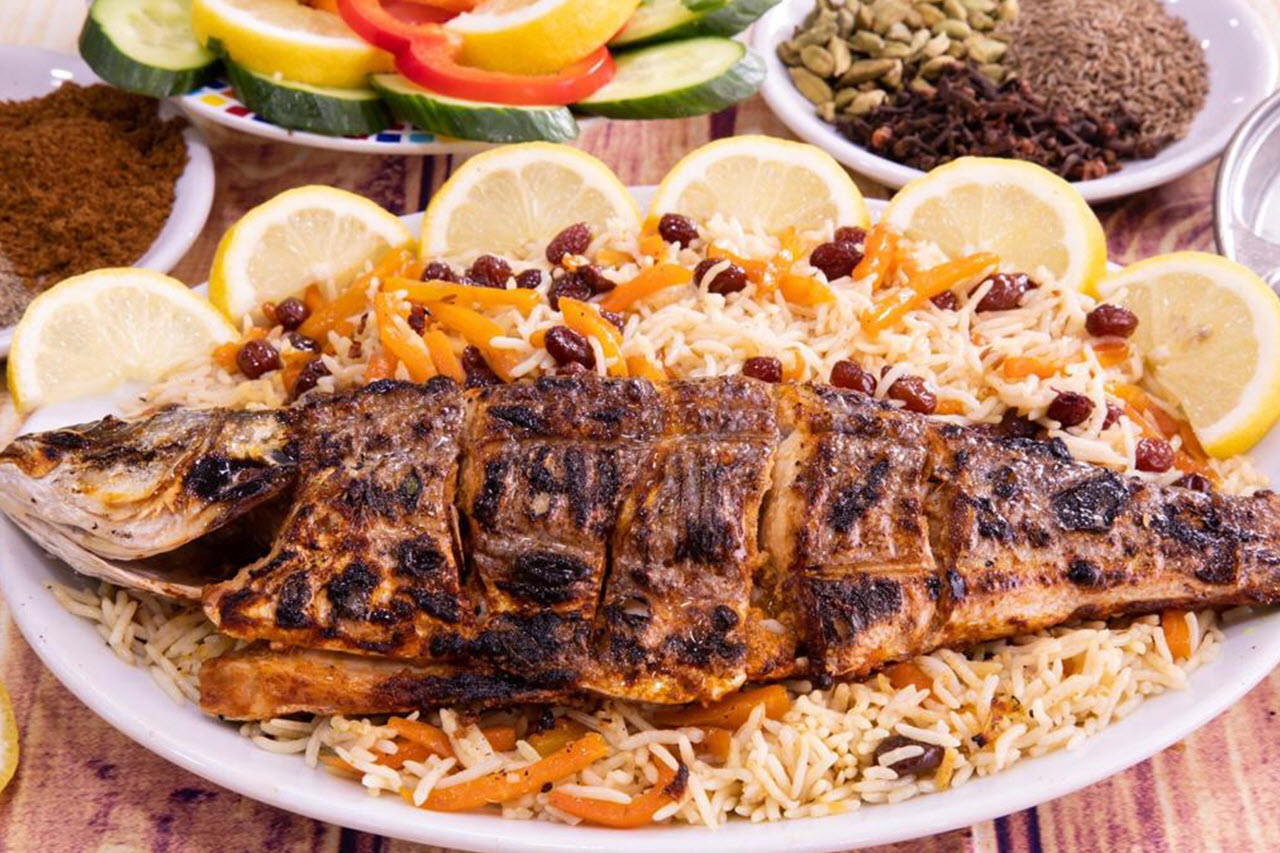 Whole charcoal-grilled sea bass with lemon slices and qabuli rice